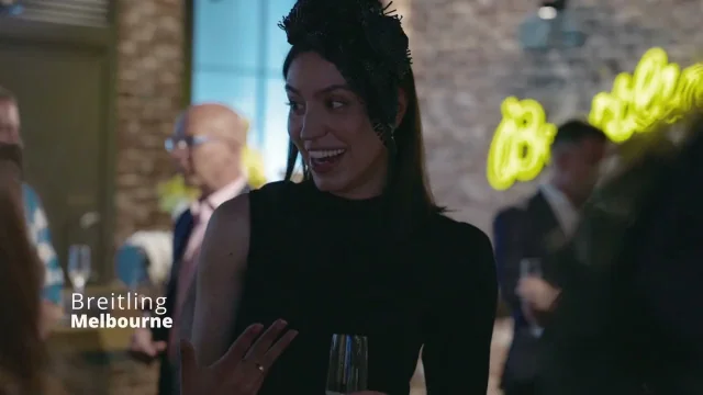Guest laughing at a Breitling evening event under a neon sign