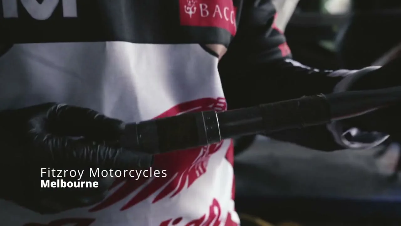 Close-up of a rider’s leather glove and red and white racing suit
