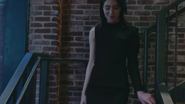 Woman in a black dress walking down a stairwell beside a brick wall